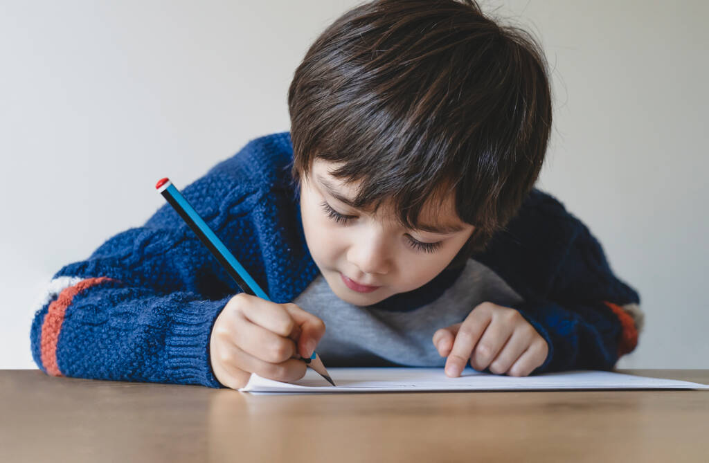 Child holding pencil writing