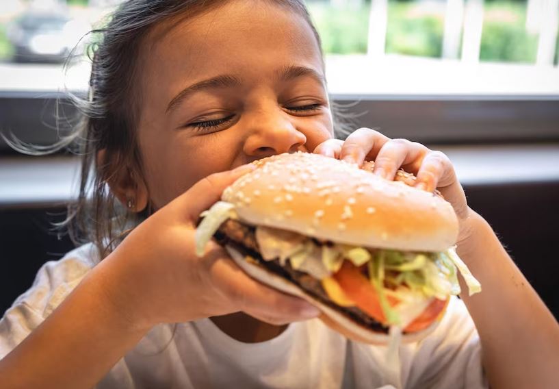 A little girl eats a burger 