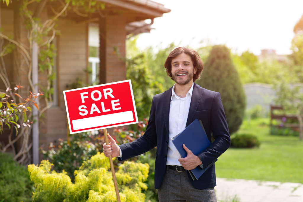 real estate agent holding FOR SALE sign