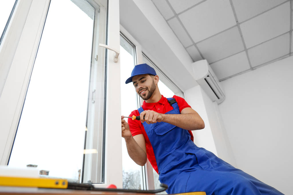 Young worker installing window in flat