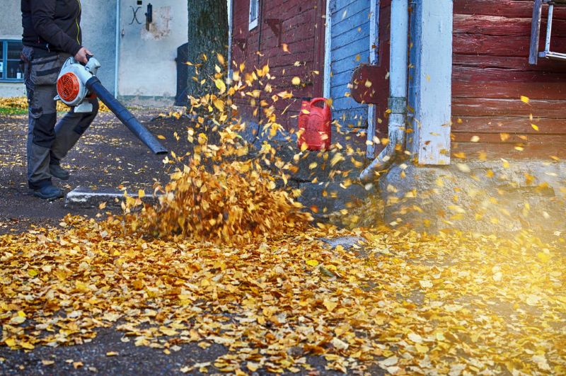 Female worker with leaf blower in the fall.