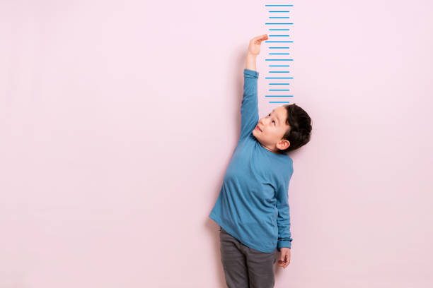 Child measuring his height on wall. He is growing up so fast. Growth Chart Decals are a Nursery Essential