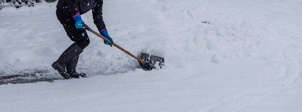 Young man shoveling snow from the walking path in winter. Must-Do Tasks To Prepare Your Concrete Driveway For Winter