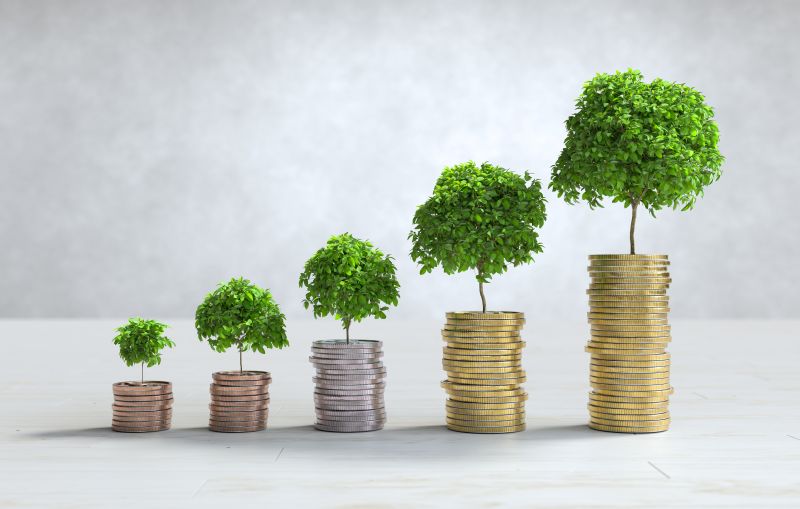 Stacks of coins arranged as a bar graph with growing green trees to illustrate green refinancing ROI.