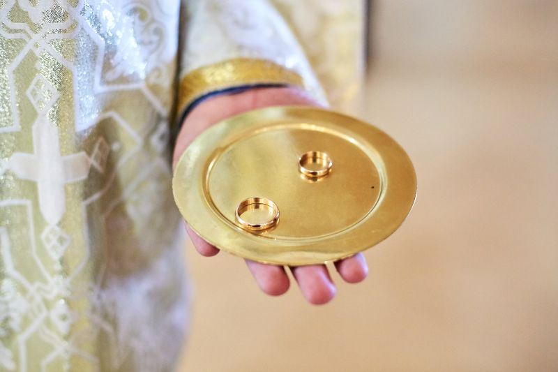 priest holds plate with golden wedding rings Wedding Bands for Women Across Different Cultures