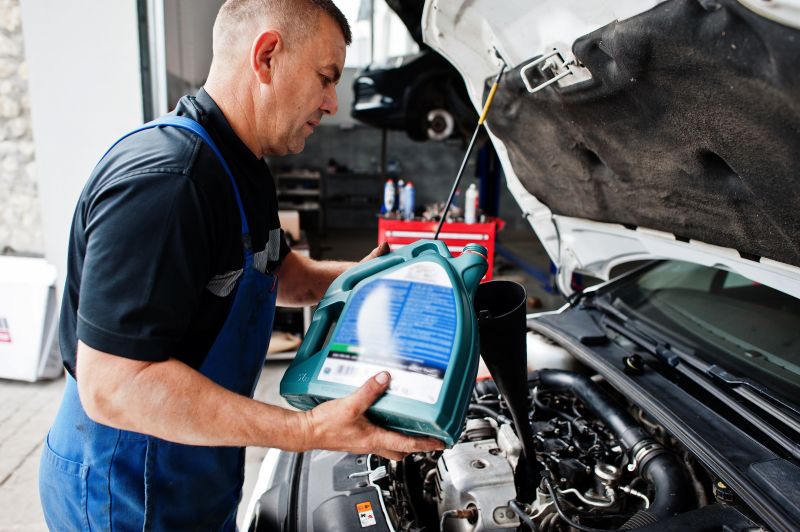 car repair maintenance theme mechanic uniform working auto service pouring new motor oil Car Engine Oil: Leading the Charge in Eco-Conscious Carsuniform working auto service pouring new motor oil